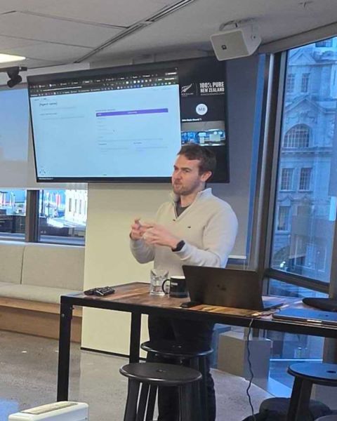 Mike presenting beside a screen and laptop